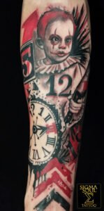 Tatuaje trash polka en negro y rojo con niño payaso, reloj y símbolos numéricos, realizado en Sigma Soul Tattoo en Carmona – Sevilla.