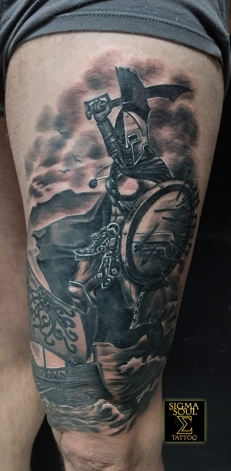 Tatuaje realista en blanco y negro de un guerrero espartano con escudo y casco frente al mar, realizado en Sigma Soul Tattoo, Carmona – Sevilla.