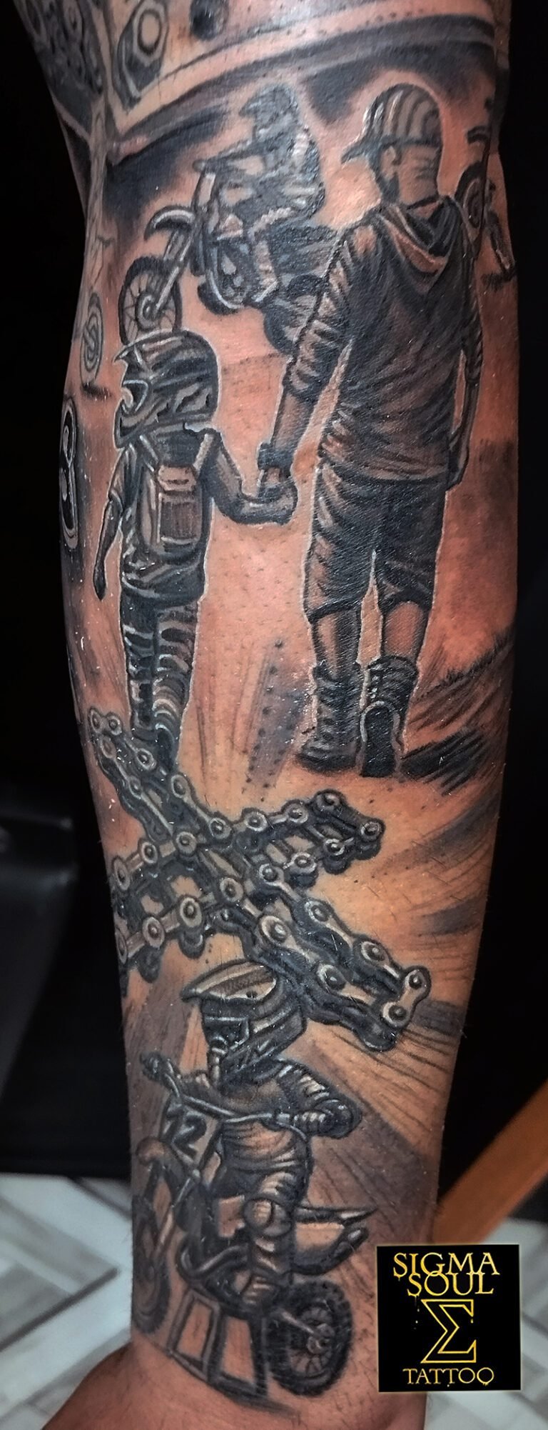 Tatuaje realista en blanco y negro de un padre e hijo con casco caminando juntos hacia las motos, con detalles de cadena y motoristas en acción, realizado en Sigma Soul Tattoo en Carmona – Sevilla.
