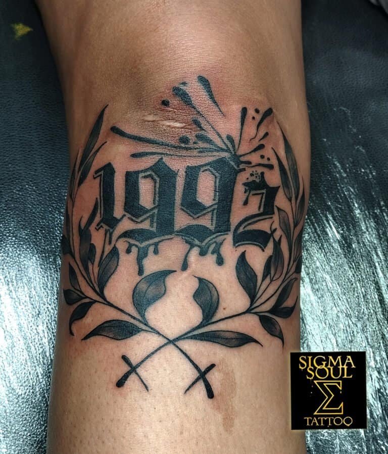 Tatuaje de la fecha 1992 en tipografía gótica blackwork, con ramas ornamentales, realizado en Sigma Soul Tattoo Studio en Carmona, Sevilla.